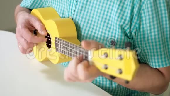 一个人在黄色的四弦琴上演奏视频的预览图