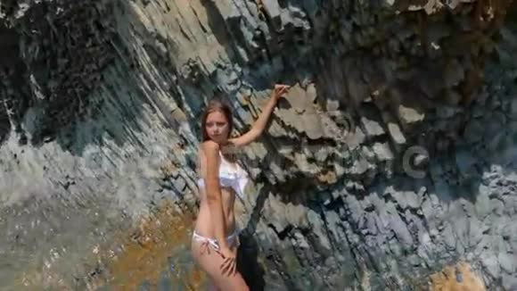 穿着白色比基尼的长直发光着脚站在悬崖附近的大海里的嫩模视频的预览图