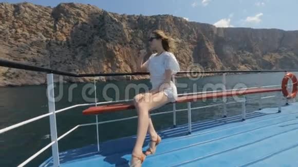 穿着白色裙子的金发女郎坐在游艇上的长凳上享受着乐趣视频的预览图