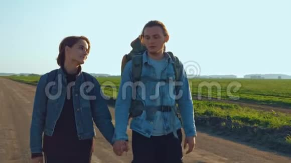 远足者和旅行者一个带着女孩的年轻人肩上扛着背包沿着播种的麦田行走视频的预览图