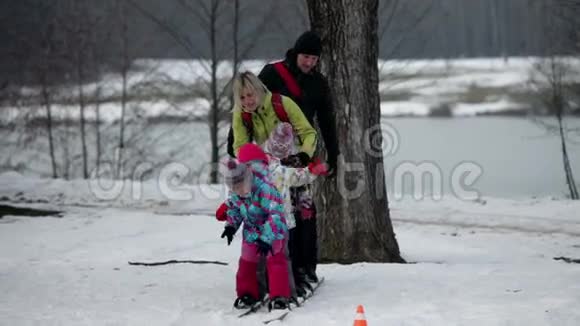 当一家人试图在雪地上踩大滑雪板时孩子摔倒了视频的预览图