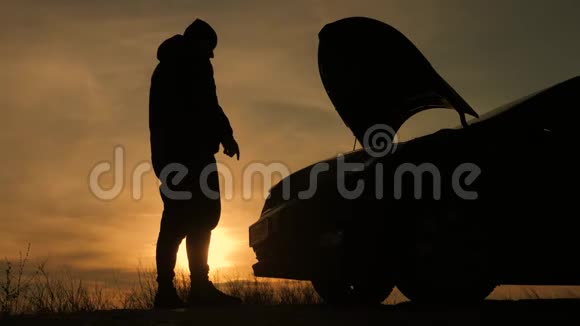 日落时剪影人正在检查那辆破车的发动机舱视频的预览图