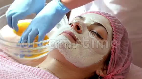 女人被用亮黄色的海绵从面罩上洗掉化妆程序视频的预览图