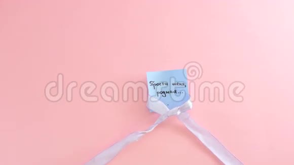 蓝色丝带系在粉红色背景的一张纸上的蝴蝶结上视频的预览图