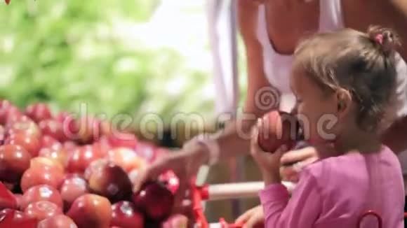 年轻的母亲带着小女儿在超市里挑选水果视频的预览图