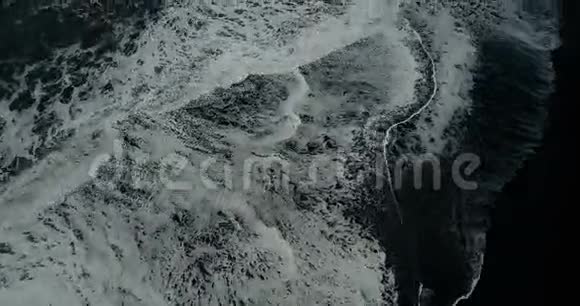 在冰岛黑色火山海滩的海岸上看到了泡沫形成的海浪视频的预览图
