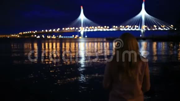 一对男女看着夜城夜晚城市的灯光在水面上闪烁斜拉视频的预览图