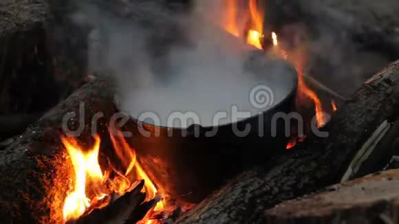 火焰围绕着锅晚上在火上做饭站在火上煮汤的锅里特写视频的预览图
