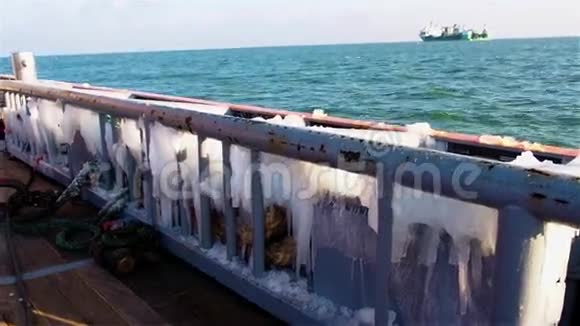 在寒冷的天气里在阳光明媚的冬日从覆盖着冰的木板上观看遥远的海上绿色船只视频的预览图