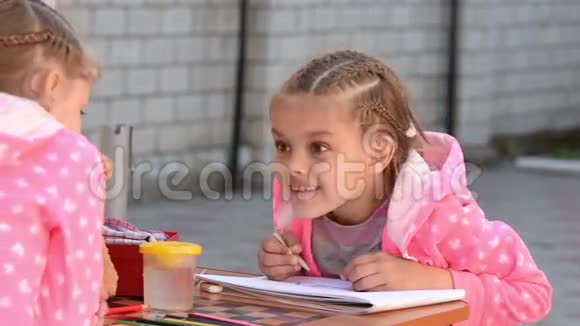 在专辑里画画的女孩和另一个女孩有感情地交谈视频的预览图