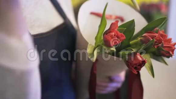 把红玫瑰放在一个锥形盒子里紧紧地握着花店老板的手视频的预览图