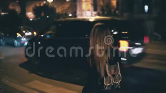 布鲁内特女士背着背包走得很晚迷人的女孩晚上穿过靠近道路的市中心视频的预览图
