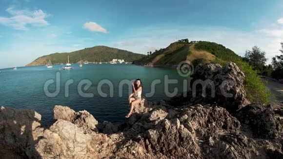年轻女子坐在岩石上旅行概念视频的预览图