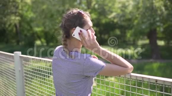 漂亮的年轻女子白天在公园里用手机视频的预览图