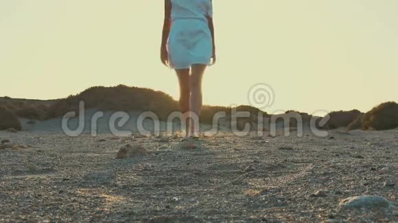 穿着白色连衣裙的女孩从日落走到相机沙漠视频的预览图