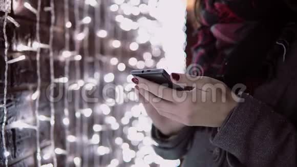 在圣诞节的夜晚一位年轻的女士用智能手机在降雪中站在视频的预览图