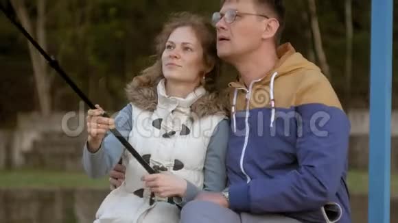男人和女人微笑着在公园里用智能手机自拍视频的预览图