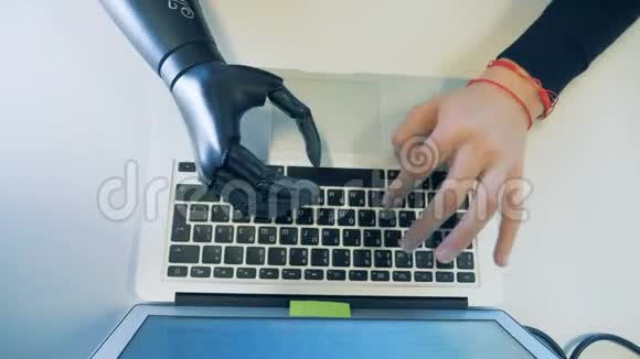 男性半机械手与人工机械手仿生假肢在计算机上工作视频的预览图