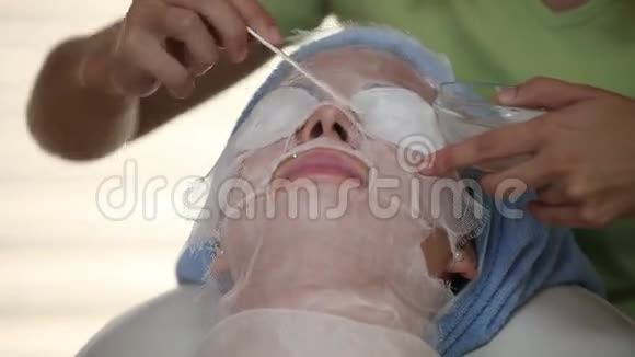 女性治疗师特写镜头为女性面部皮肤添加物质视频的预览图