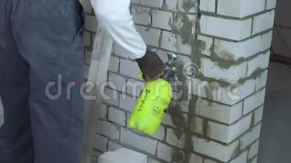 建筑工人用喷水器湿润砖墙视频的预览图