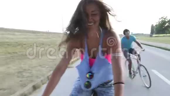 年轻漂亮的女人骑自行车时摆姿势和高拍她的朋友视频的预览图