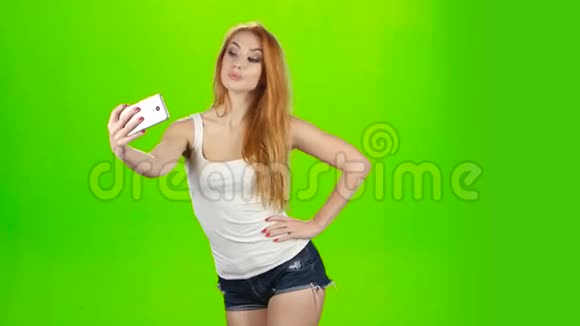 自拍手机上的照片摆红发女孩模特工作室视频的预览图