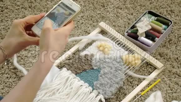 一个女人在织布机上织着一件由纱线制成的美丽刺绣在一家家庭工作室里电话里有照片视频的预览图