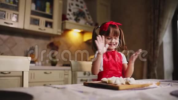 厨房里的小女孩在玩面团和面粉拍手笑了起来在厨房里胡闹视频的预览图