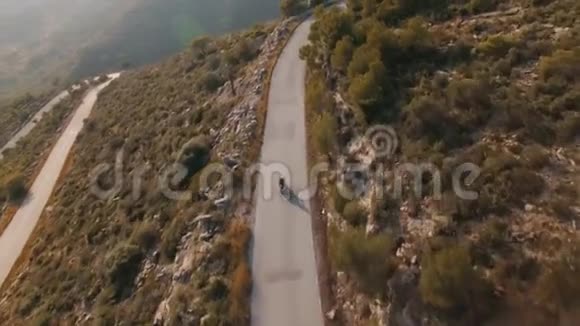孤独的旅行者骑着摩托车在壮丽的山路上的无人机镜头视频的预览图