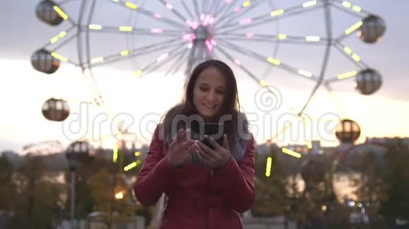 美丽的黑发年轻女子在夜城的街道上散步时使用手机美丽的灯光闪闪发光视频的预览图
