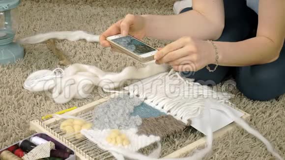 一个女人在织布机上织着一件由纱线制成的美丽刺绣在一家家庭工作室里电话里有照片视频的预览图
