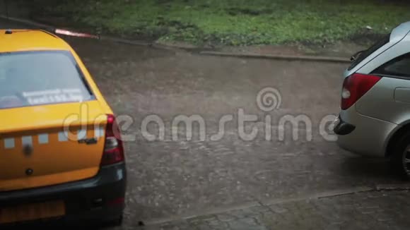 雨水倾泻在人行道上一辆出租车和一辆汽车变成了洪水另一辆车经过下面的水溅到周围视频的预览图