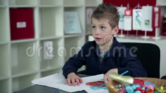 小男孩在幼儿园用蓝色铅笔画画视频的预览图