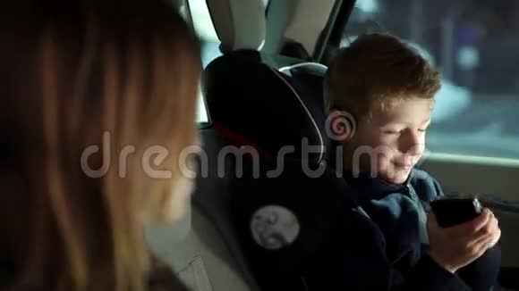 小男孩在车里敲手机视频的预览图