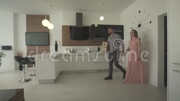 兴奋的年轻夫妇环视室内厨房现代时尚设计在4k拍摄的新公寓中移动视频的预览图