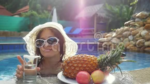 年轻女子戴着帽子戴着太阳镜边喝水边晒太阳边吃水果和李子视频的预览图