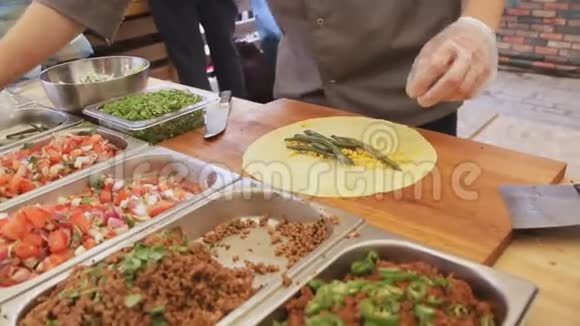 专业厨师正在街头美食节上用皮塔和蔬菜制作玉米饼烹饪过程接近视频的预览图