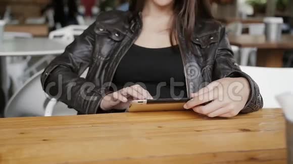 时尚的年轻女性使用平板电脑发送短信坐在现代咖啡馆的桌子上奇迹微笑视频的预览图