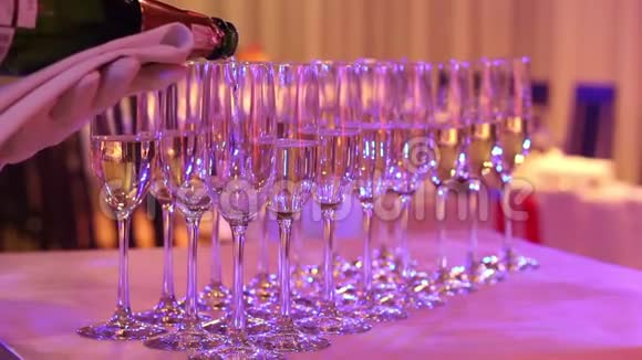 服务员把香槟倒入玻璃杯中香槟杯放在自助餐桌上餐厅或酒店的大厅视频的预览图