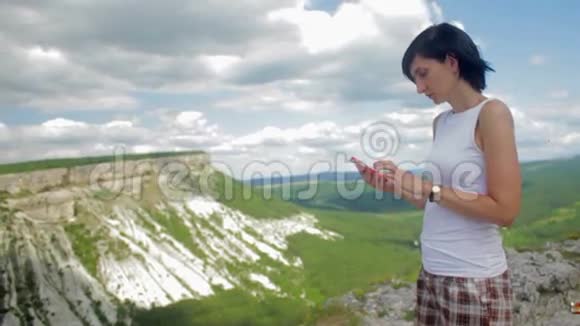 有魅力的女人在山上的智能手机上发短信视频的预览图