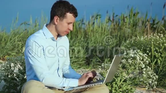 一个拿着笔记本电脑坐在沙滩上的人自由职业者视频的预览图
