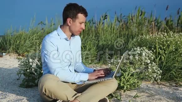 一个拿着笔记本电脑坐在沙滩上的人自由职业者视频的预览图