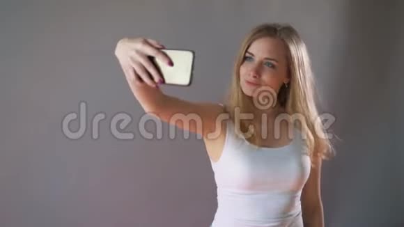 淡妆的美女在灰色背景上自拍视频的预览图