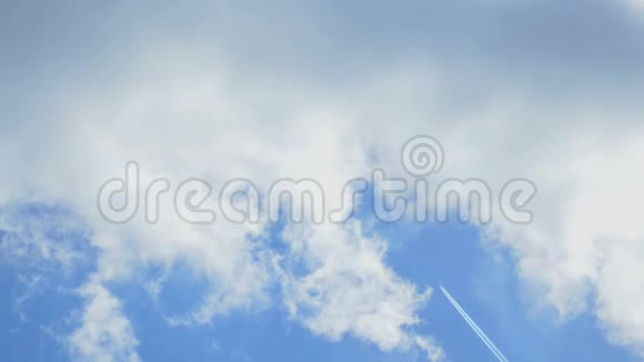 一架遥远的飞机从高空飞过在多云的蓝天上留下一个喷气式飞机的轨迹风视频的预览图