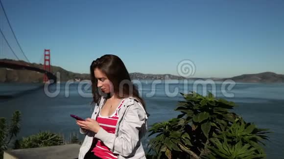 金门大桥使用智能手机的女人视频的预览图