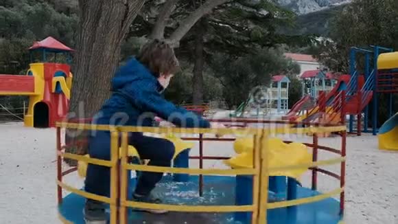 一个小男孩在操场上骑旋转木马视频的预览图