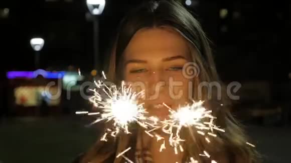 年轻的微笑女孩手里拿着火花慢镜头中拿着火花的女孩肖像视频的预览图