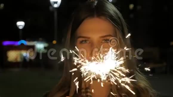 年轻的微笑女孩手里拿着火花慢镜头中拿着火花的女孩肖像视频的预览图