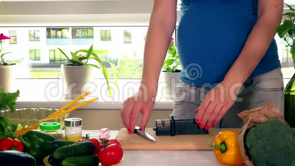 孕妇妻子用家庭厨房专用工具磨刀视频的预览图