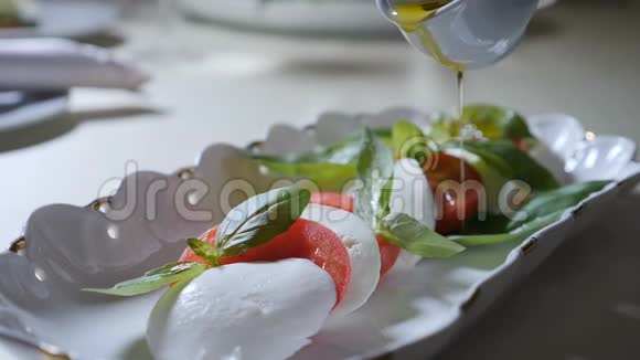 健康食品和素食理念将橄榄油倒入卡普雷斯色拉意大利辣椒色拉和视频的预览图